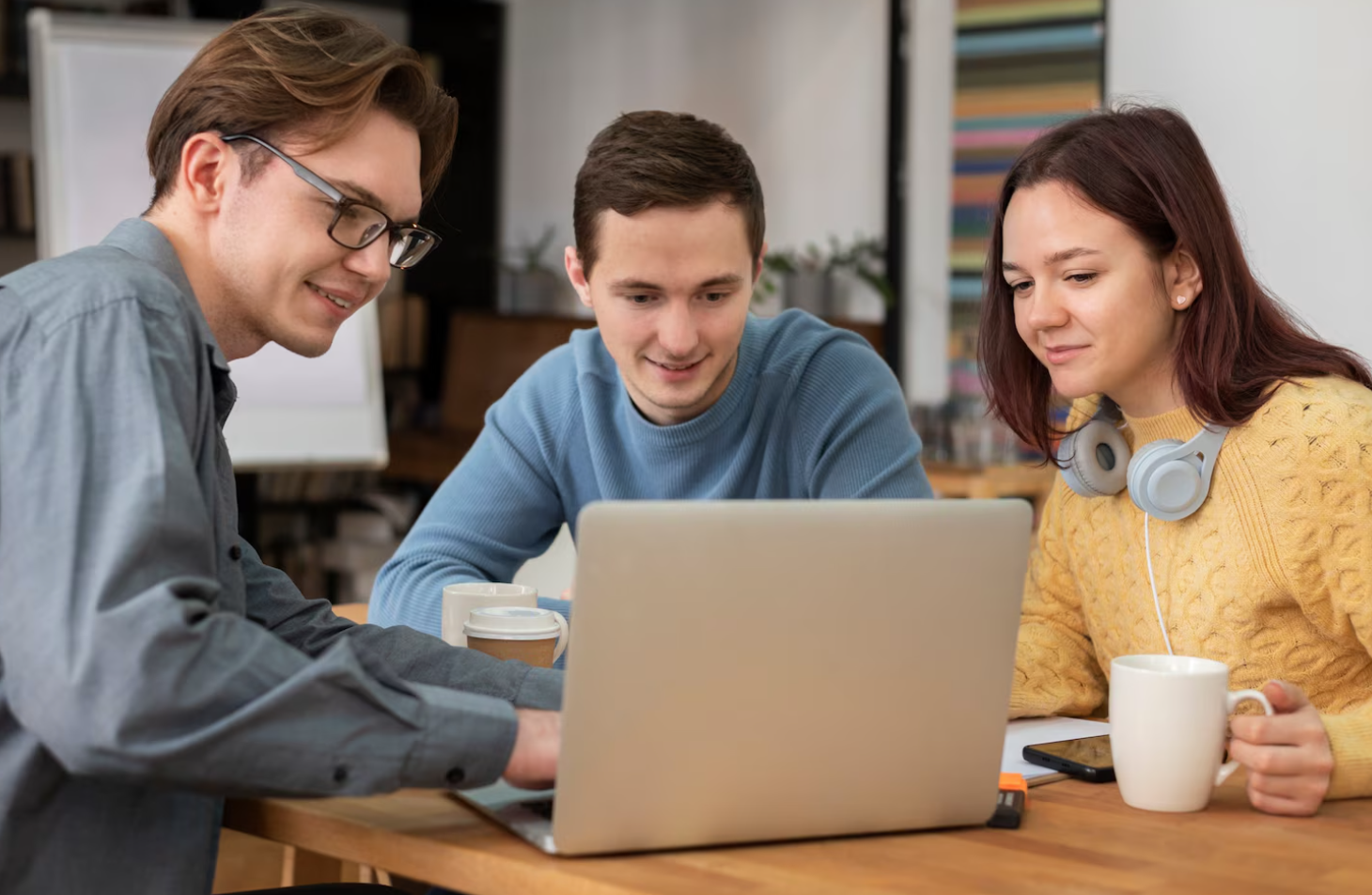 A group of three people discussing in a front of a laptop