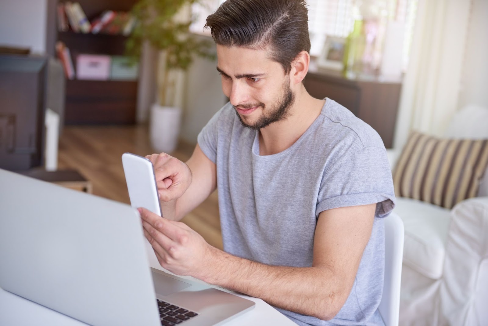 A man uses a healthcare website on his mobile device while a laptop sits on the table, entering information on a secure platform