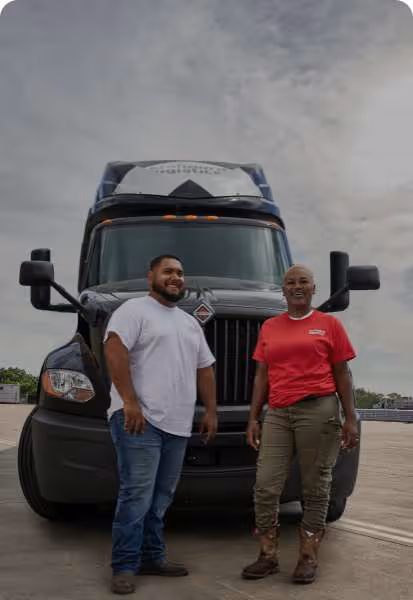 Two workers smiling in front of a Standard Logistics truck outside.