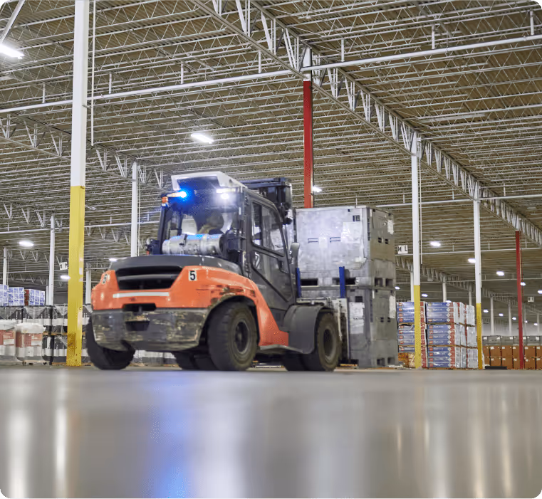 A vehicle transporting stacked containers inside a warehouse.