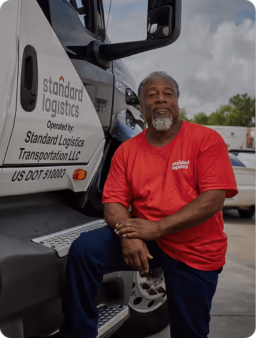 A man sitting next to a Standard Logistics truck.