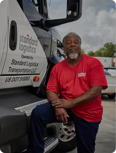A man sitting next to a Standard Logistics truck.