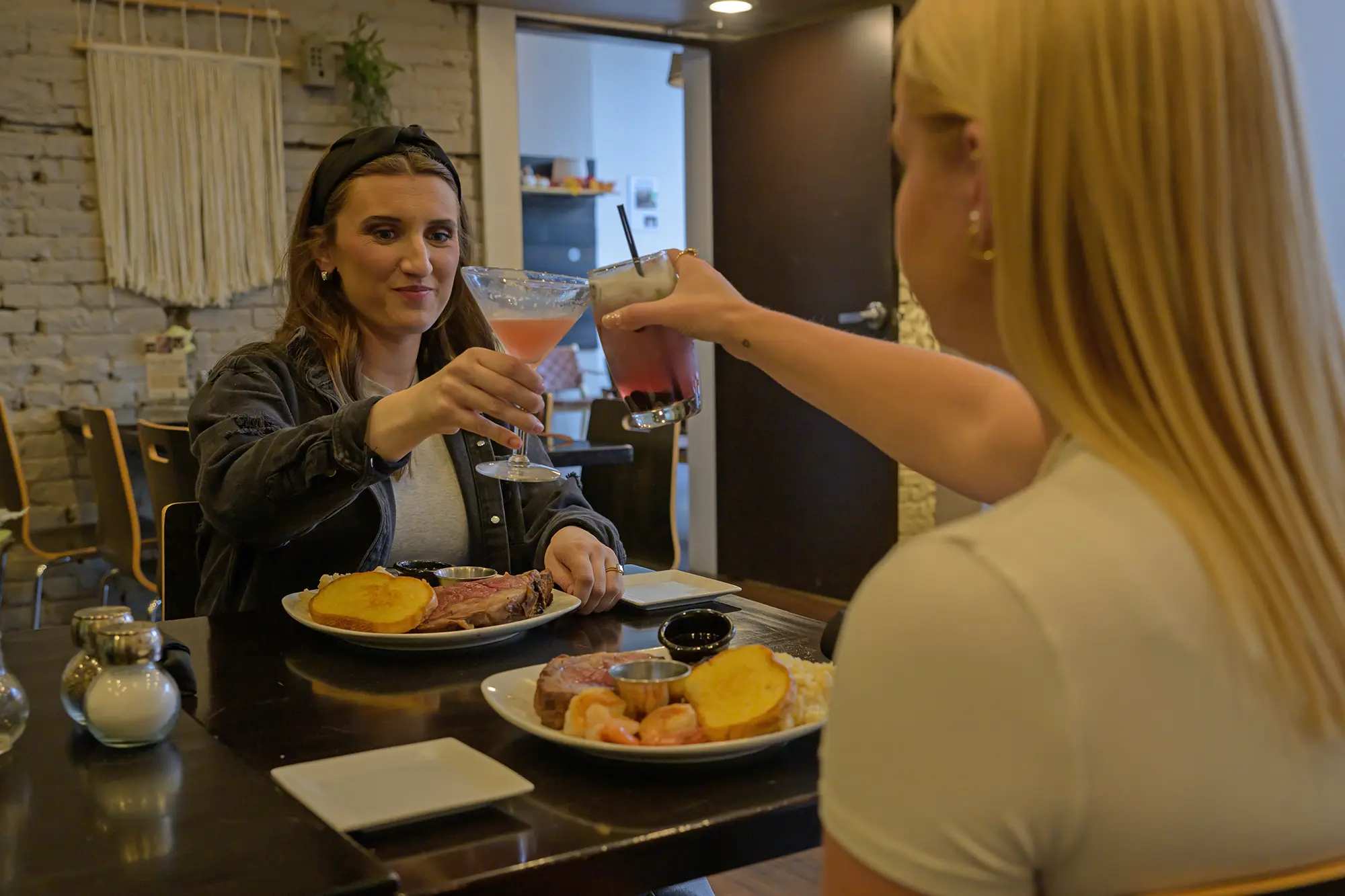 Two young women raise their glasses over prime rib meals at Grand Island's  Chocolate Bar in the Railside district.