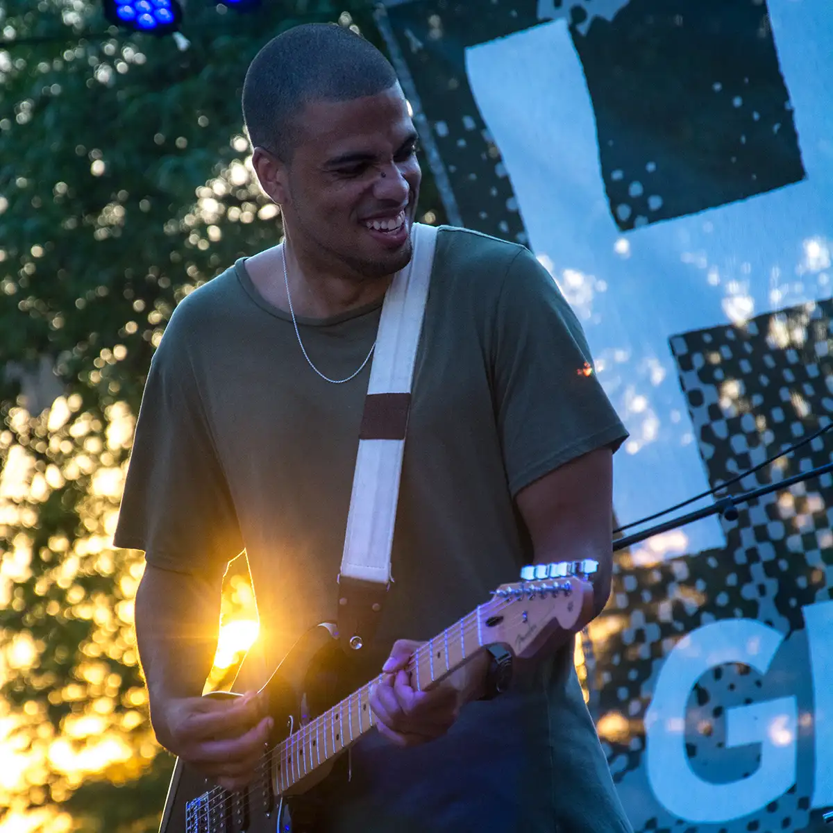 The sun sets behind a guitarist at a free summer concert.