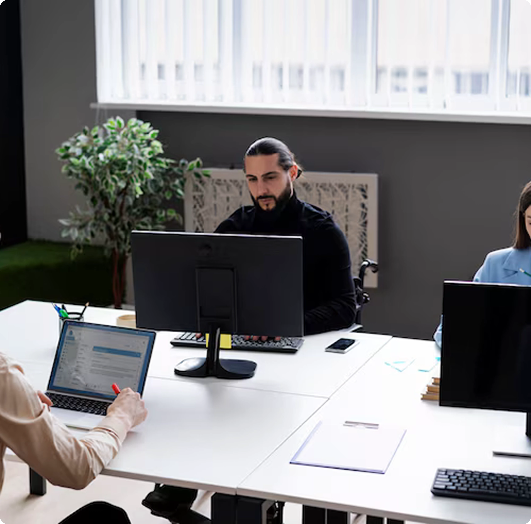 A group of people sitting around a table with computers.