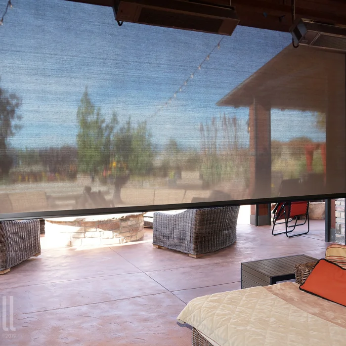 Outdoor solar shade with visible patio furniture reflected in surface