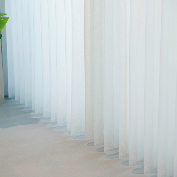 Bottom view of soft white vertical blinds aligned neatly along the floor 
