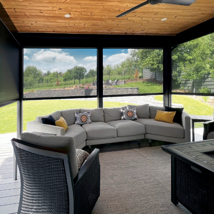 Cozy patio with black mesh shades and sectional sofa under wood ceiling