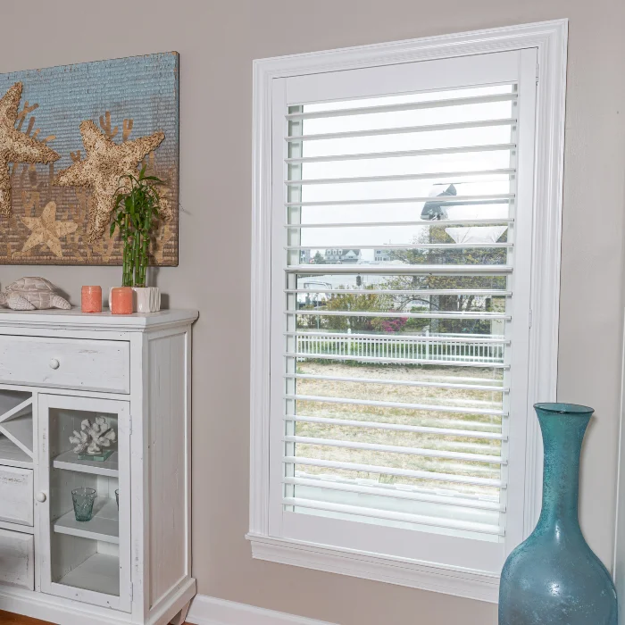 Close-up of two white plantation shutter panels, with their louvers slightly open