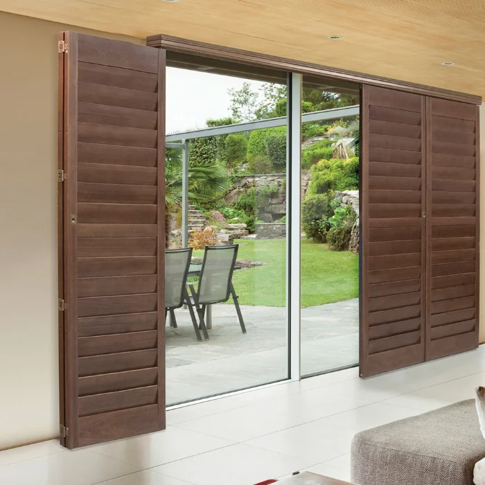 Dark brown bi-fold plantation shutters on a sliding glass door leading to a patio