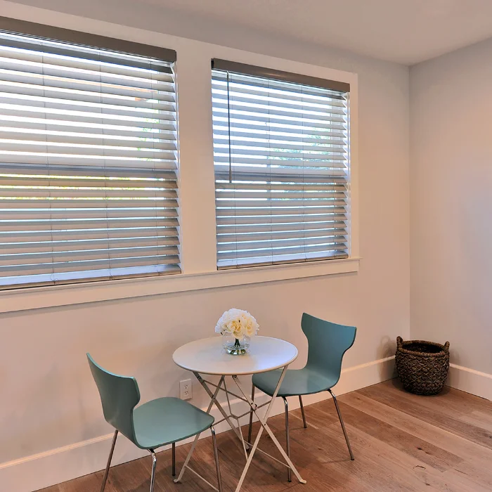 Minimalist breakfast nook with white faux wood blinds and teal chairs