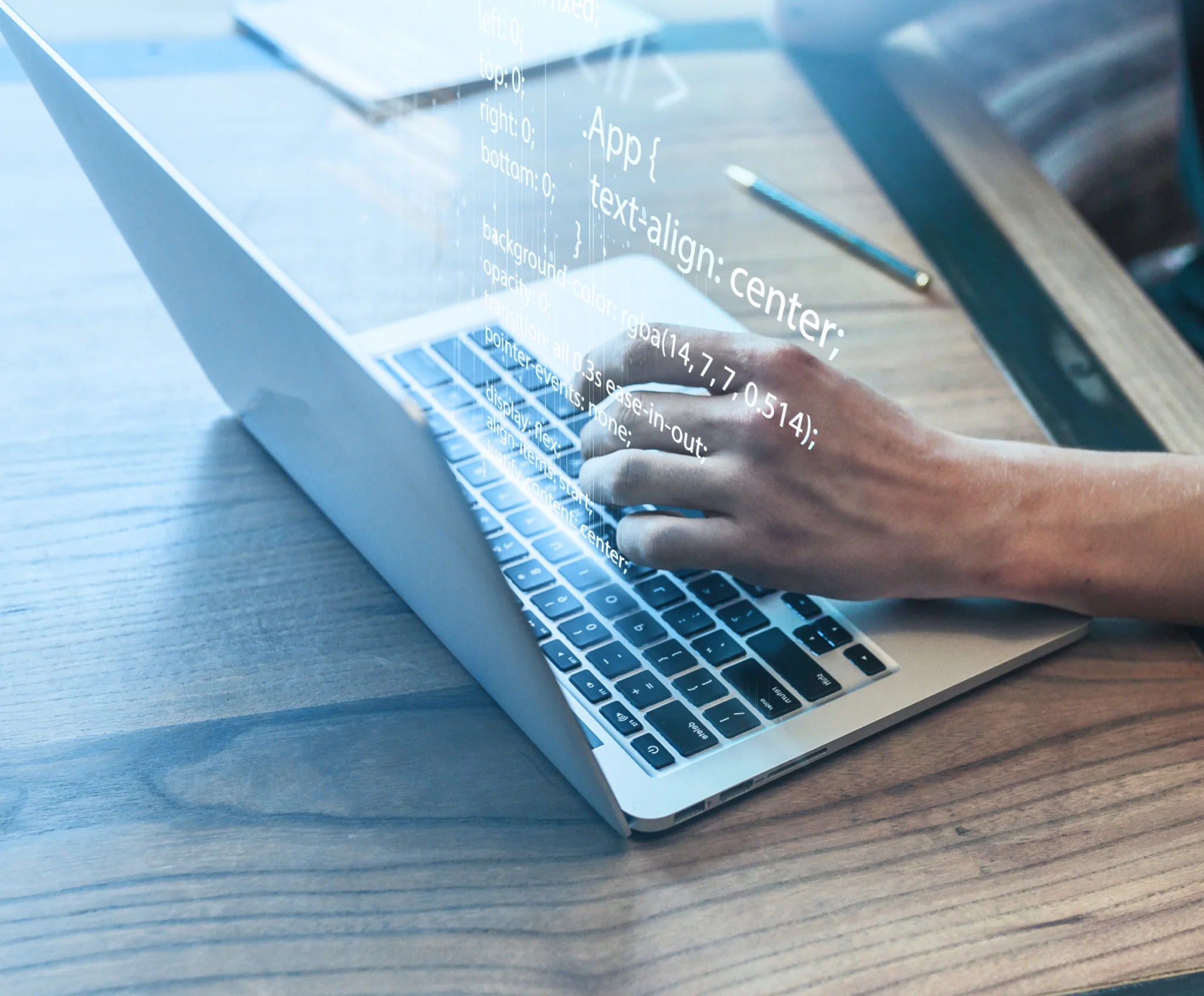A person typing on a laptop on a wooden table.