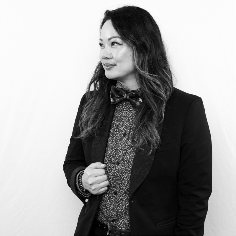 Black and white portrait of a woman in a floral bow tie and suit jacket looking to her left.