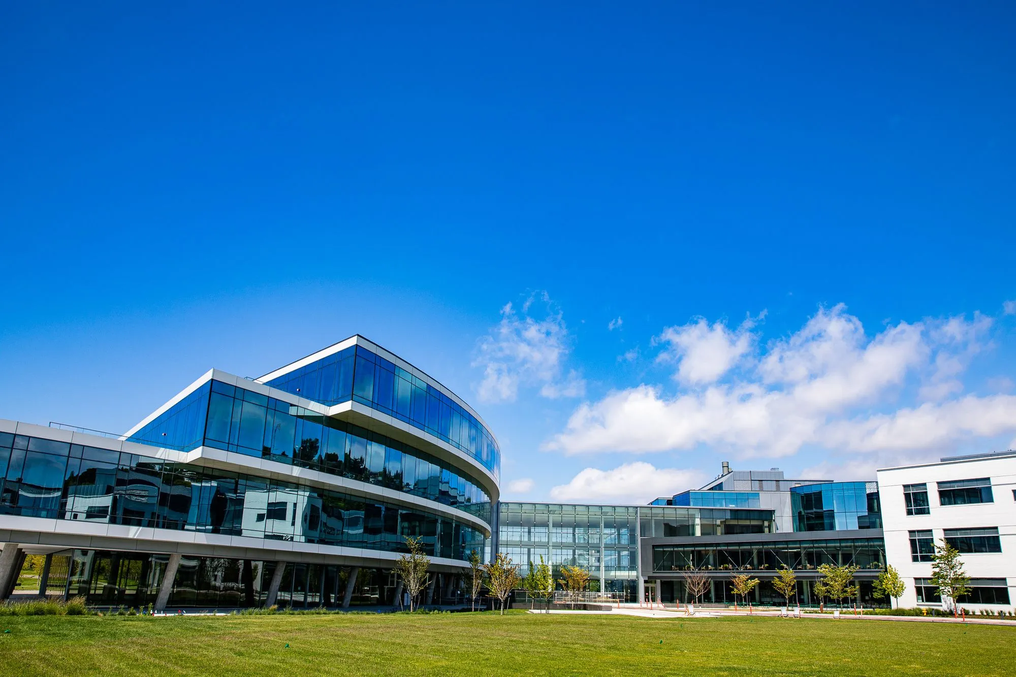 A perfectly mowed field of grass in front of a modern commercial building. 