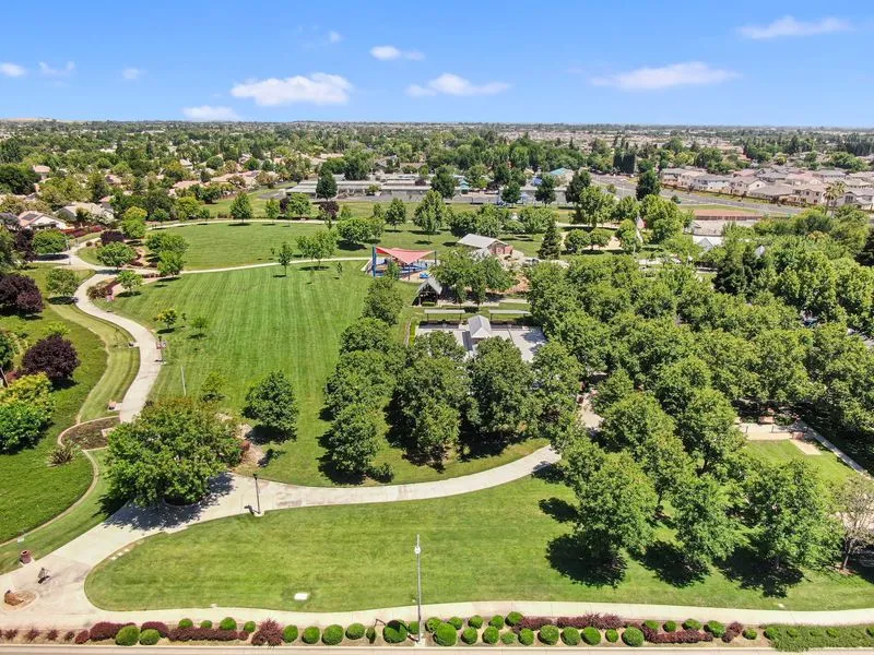 A distant view of a beautiful park that is covered with vibrant green trees and well-manicured grass. 