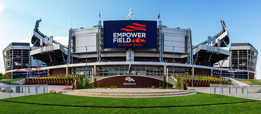 A wideshot of Empower Field at Mile High featuring its grand entrance, framed by beautifully trimmed grass.