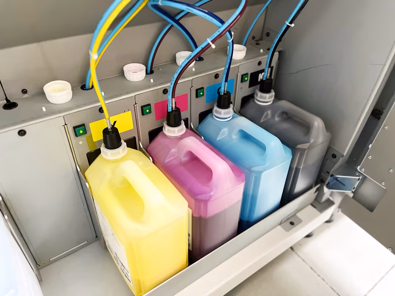 four bottles of CMYK inkjet connected to a commercial printer