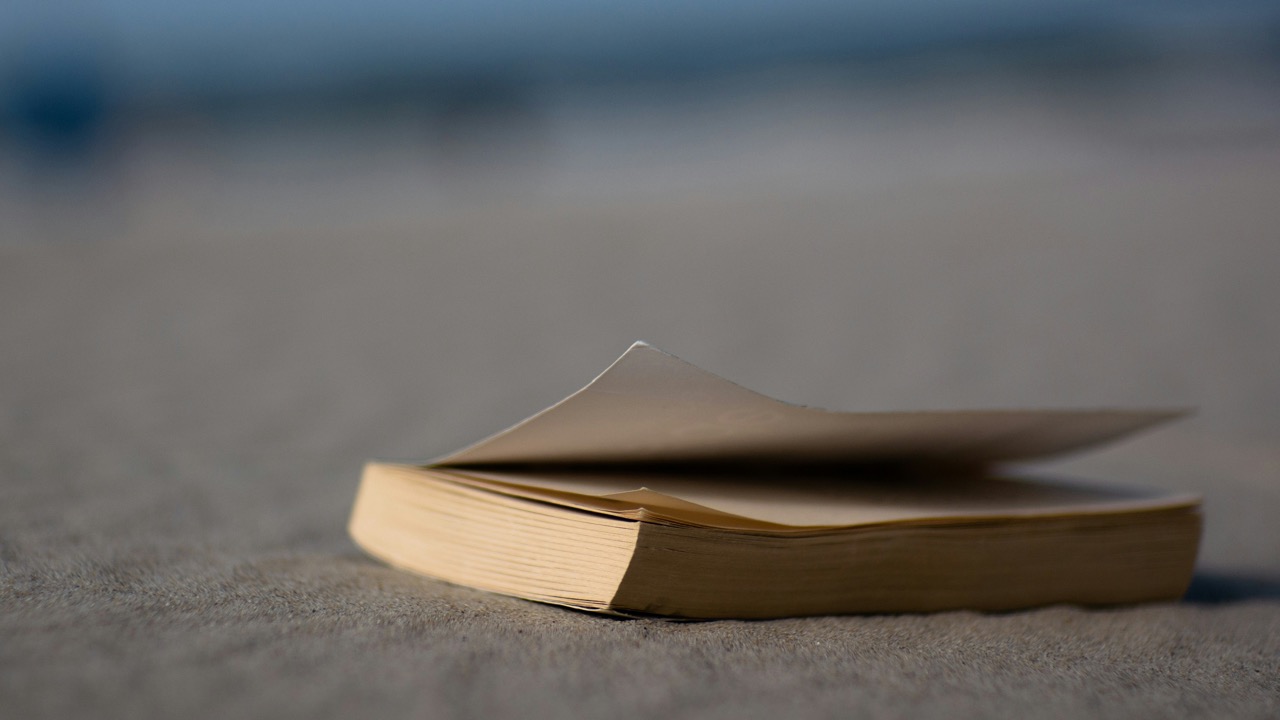 book sitting on the sand at a beach. Image source: Lennart Heim on Unsplash