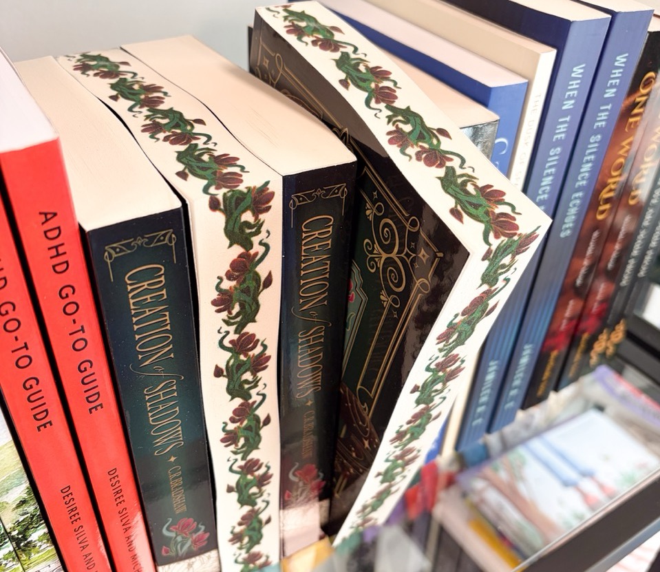 Creation of Shadows by C.R Bradshaw, with special edition sprayed edges from FolioFox, on a bookshelf full of books with the book showing its sprayed edges out