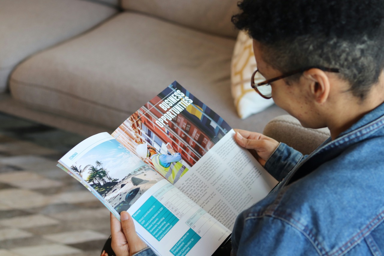person opening business saddle-stitched booklet. Image source: BETZY AROSEMENA from Unsplash.
