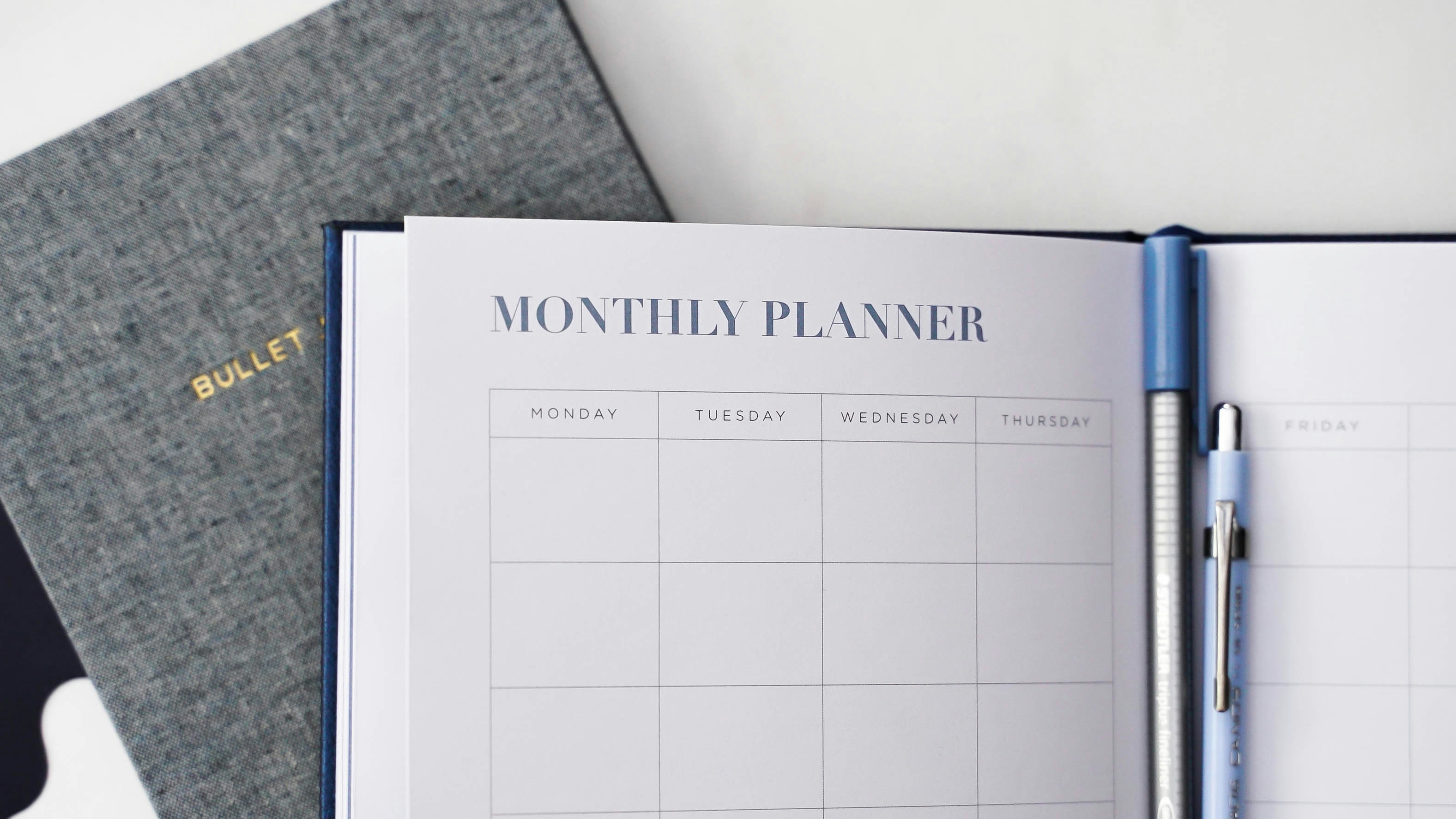 monthly planner diary open on a table with two pens inside. Source: 2H Media