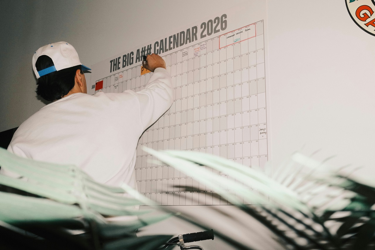 man wearing a cap, writing on a wall calendar