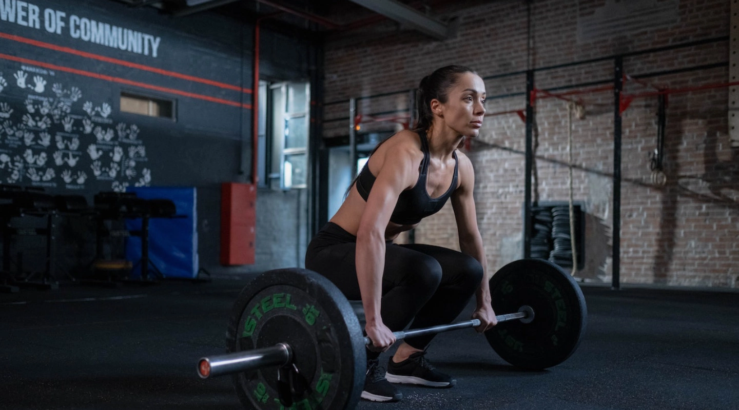 A woman squats with a barbell in a gym at Sport Performance in Lockhart, TX, focusing on strength training.