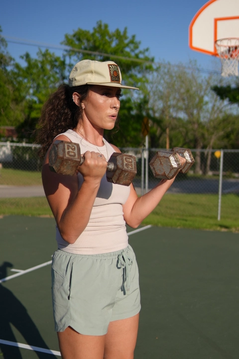 A woman holds a dumbbell, participating in a fitness program at On The Block Fitness in Lockhart, TX.