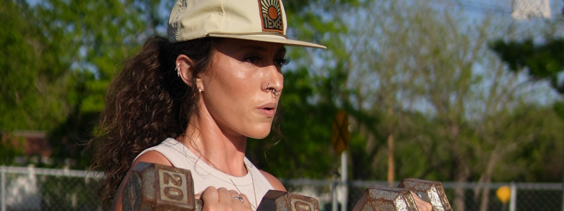A woman holds a dumbbell, participating in a fitness program at On The Block Fitness in Lockhart, TX.