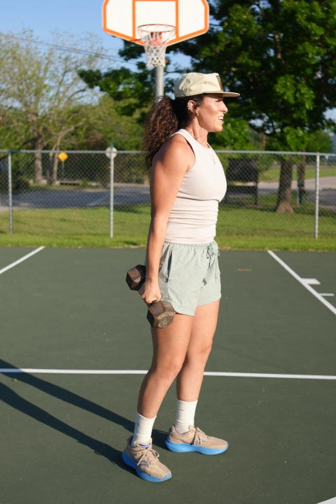 A woman stands holding a tennis racket, promoting On The Block Fitness in Lockhart, TX.