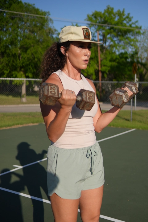  woman squats with a barbell in a garage, part of the Strength and Conditioning program at On the Block Fitness, Lockhart, TX.