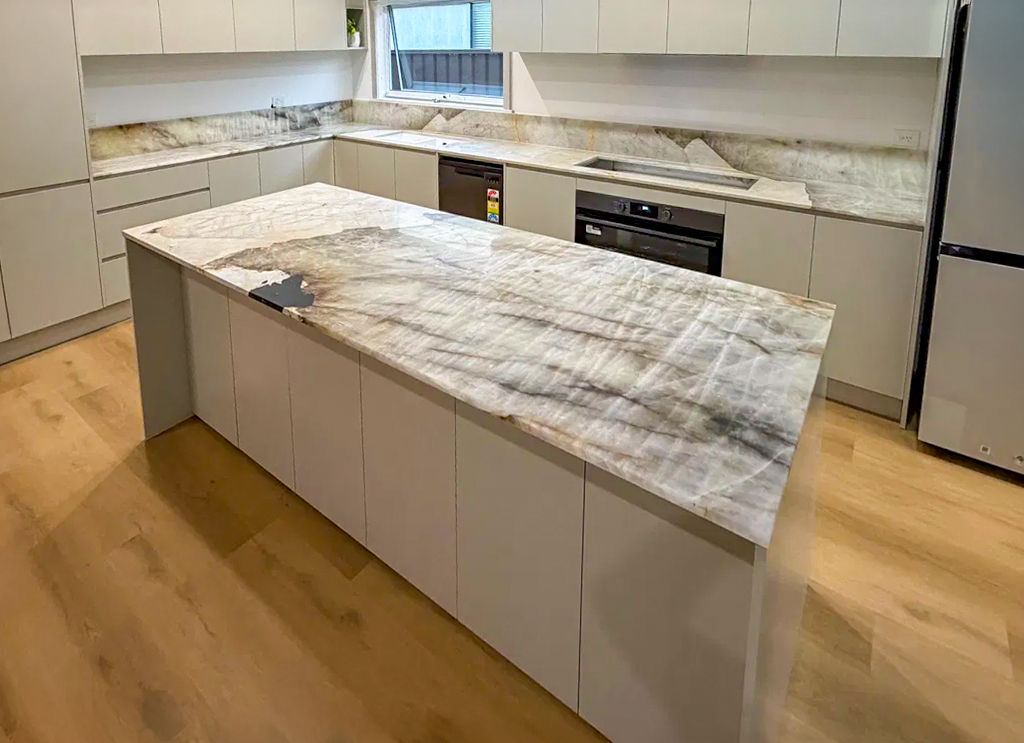 Patagonia quartzite island with a single mitred waterfall end and matching full slab splashback, light handleless joinery, Sydney kitchen by Marble Hub