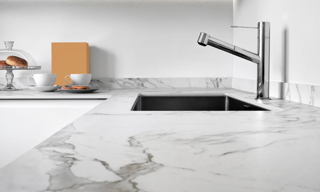 Close-up detail of a marble-look engineered stone benchtop with distinct grey veining, an undermount sink, and a modern chrome kitchen tap