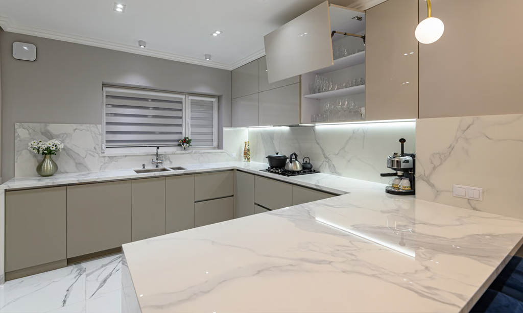 Modern kitchen design with taupe handleless cabinets and a striking white marble-look engineered stone benchtop with matching splashback.