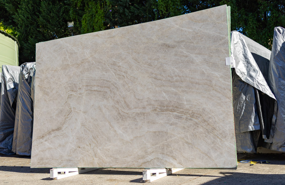 Large taj mahal quartzite slab resting outdoors, ready for fabrication into premium stone benchtops sydney