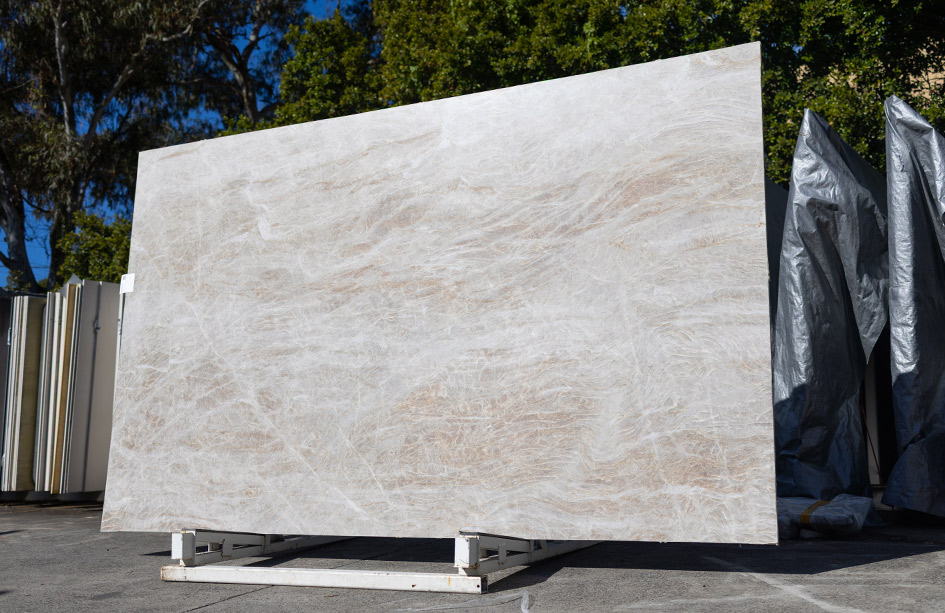 Large taj mahal quartzite slab resting outdoors, ready for fabrication into premium stone benchtops sydney