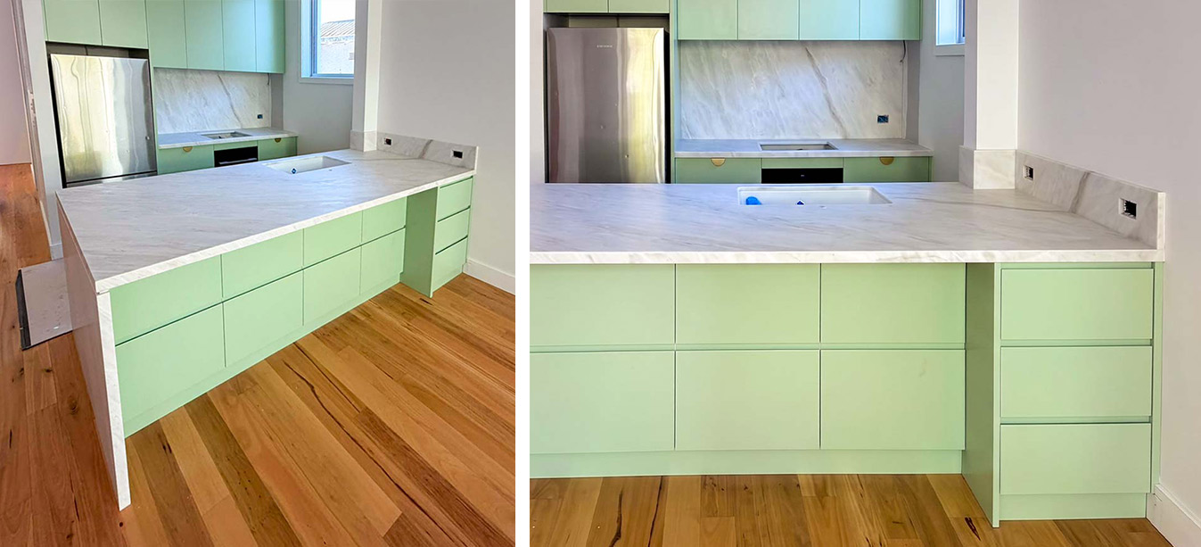 A luxury kitchen featuring pastel mint green cabinetry paired with a white marble-look natural stone benchtop and splashback. The island features a sleek waterfall edge, beautifully contrasting with warm timber floorboards.