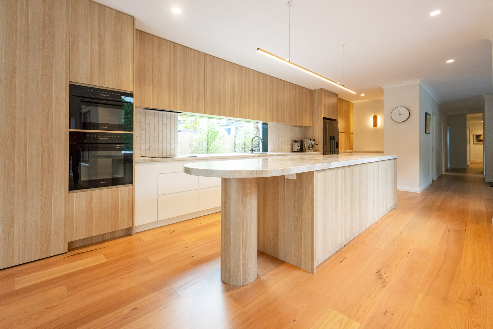 Curved oval Taj Mahal Quartzite island with cantilevered overhang on a timber column, warm cream benchtop, timber joinery, Sydney kitchen by Marble Hub