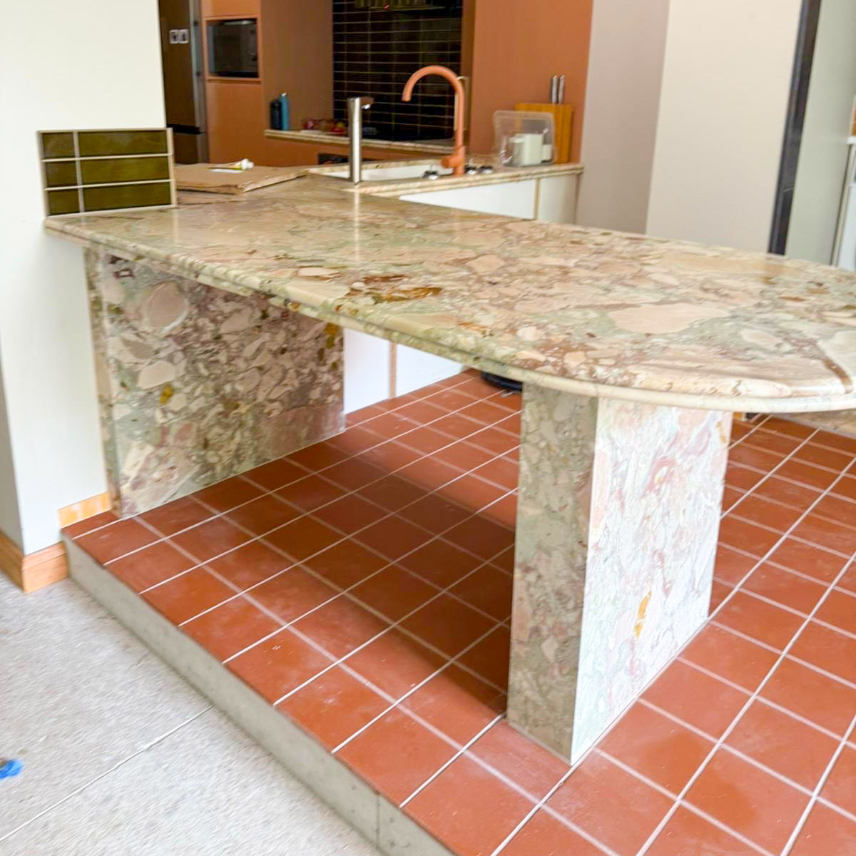 Curved oval Breccia Rose Botticelli marble island with cantilevered overhang on twin stone plinths, cream, green and rose breccia movement, Sydney kitchen by Marble Hub