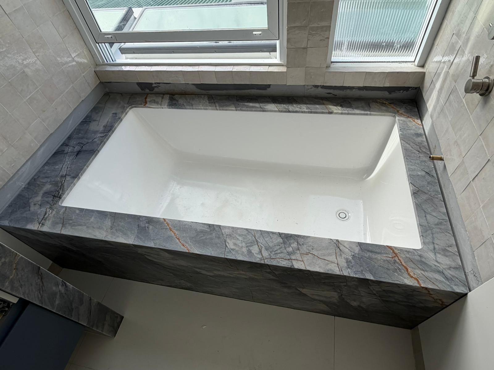 Ijen Blue quartzite bath surround, book-matched vein flow carrying over the deck edge and down the apron, undermount bath, Sydney bathroom.