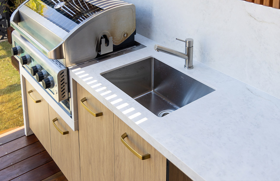 Close-up detail of an Everest Sunrise Silk Neolith Porcelain benchtop in an outdoor kitchen. The image highlights the crisp, clean mitred edge and waterfall drop, showcasing the flawless finish against timber cabinets
