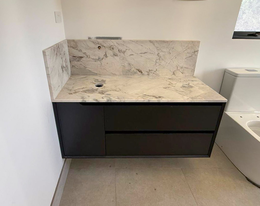 Lord White marble vanity top, thick mitred apron, floating on dark timber joinery with full-height marble splashback, Sydney bathroom