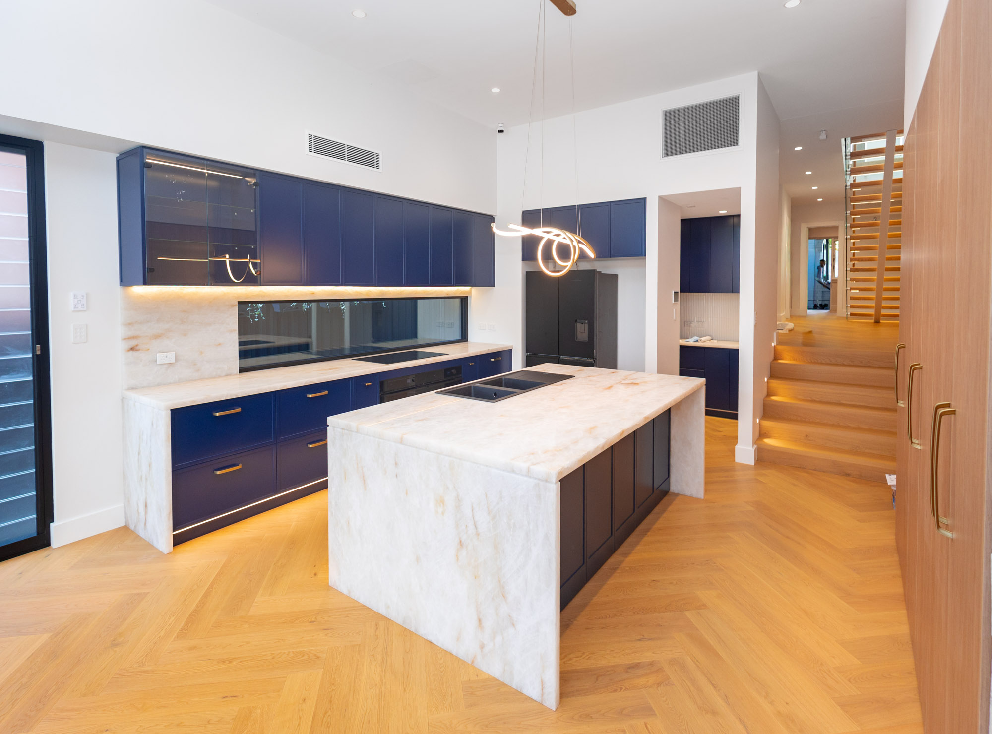 White Cristallo quartzite waterfall island with navy Ahoy joinery and brass handles, Randwick kitchen, Sydney