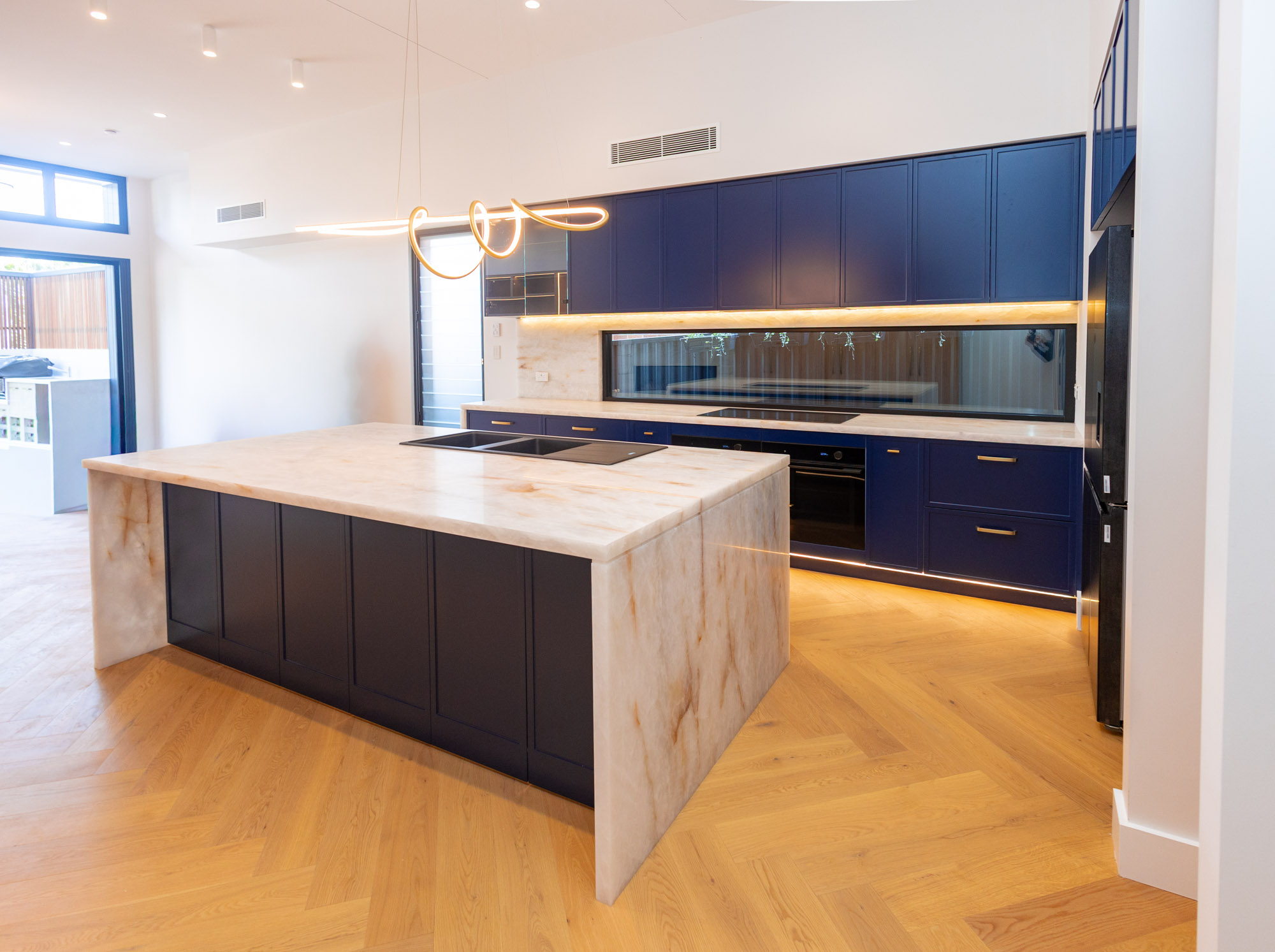 White Cristallo quartzite shadowline waterfall island over navy polyurethane cabinetry, Randwick, Sydney
