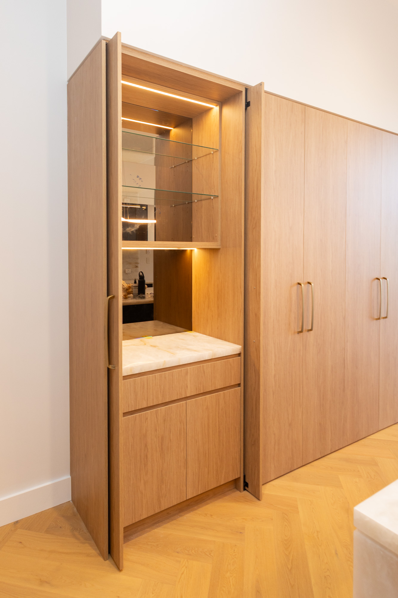 Polytec Bosten Oak Woodmatt hidden bar with lit glass shelves, stone bench and mirrored back, Randwick, Sydney