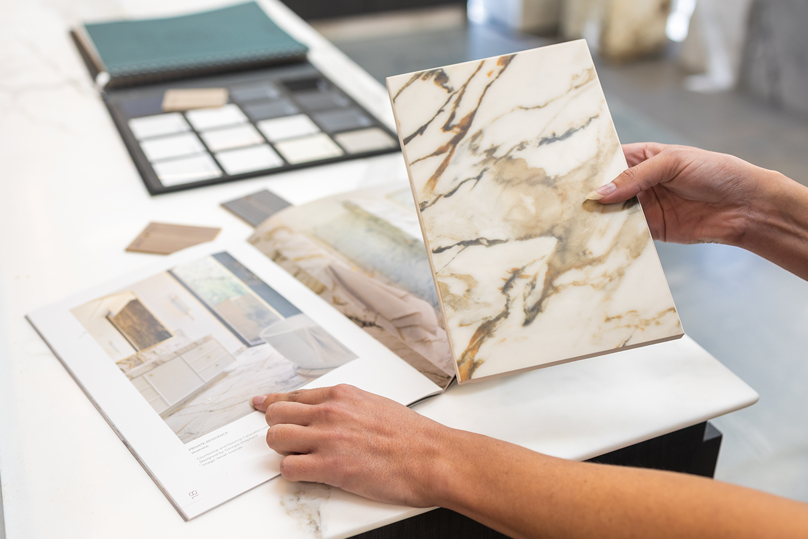 Homeowner comparing natural stone slab samples against inspiration photos under showroom light at Marble Hub Sydney