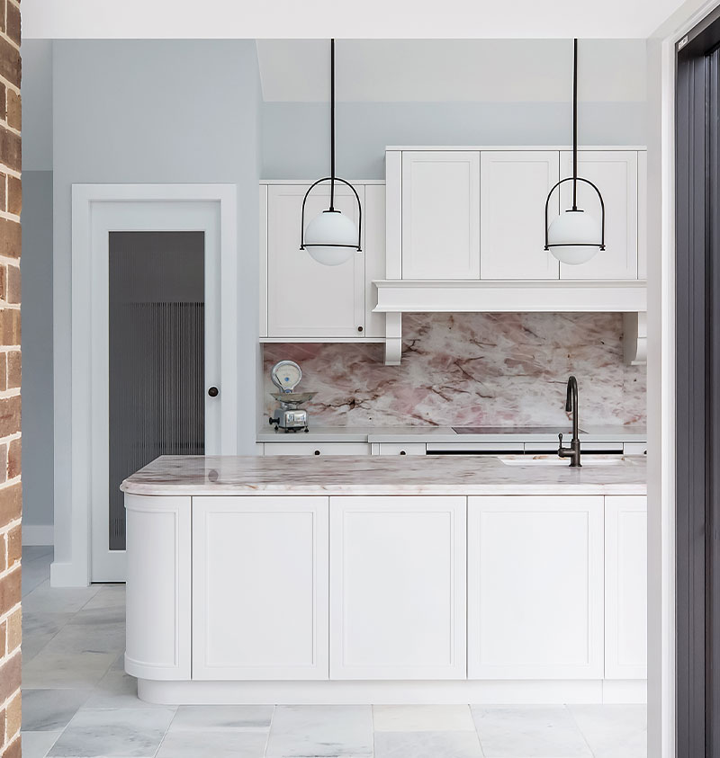 Pink Cristallo Quartzite island and splashback seen through an open doorway under a skylight, Sydney kitchen
