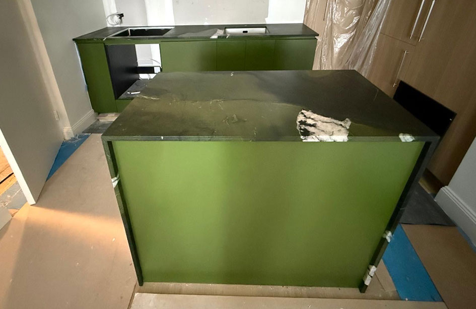 Granite benchtop and low splashback above deep green flat-panel cabinetry, Sydney