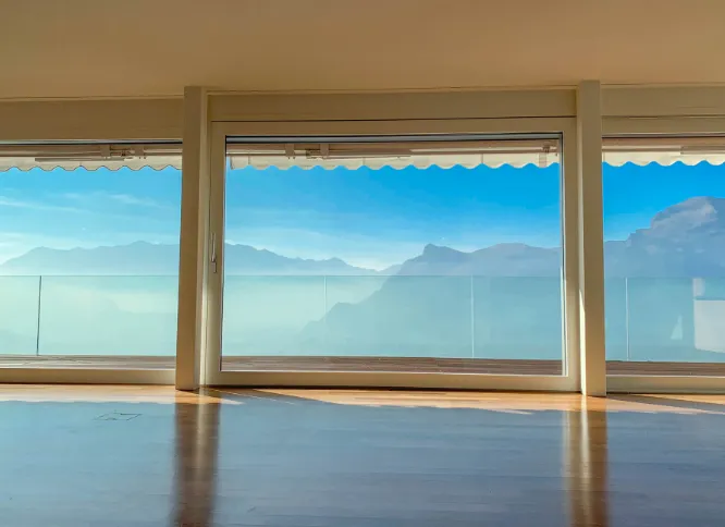 Heller Raum mit Fenstern, die eine Terrasse und ein beeindruckendes Bergpanorama in Triesenberg zeigen.