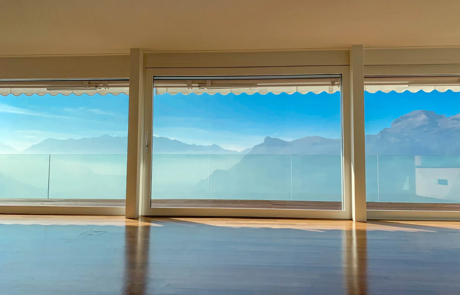 Heller Raum mit Fenstern, die eine Terrasse und ein beeindruckendes Bergpanorama in Triesenberg zeigen.